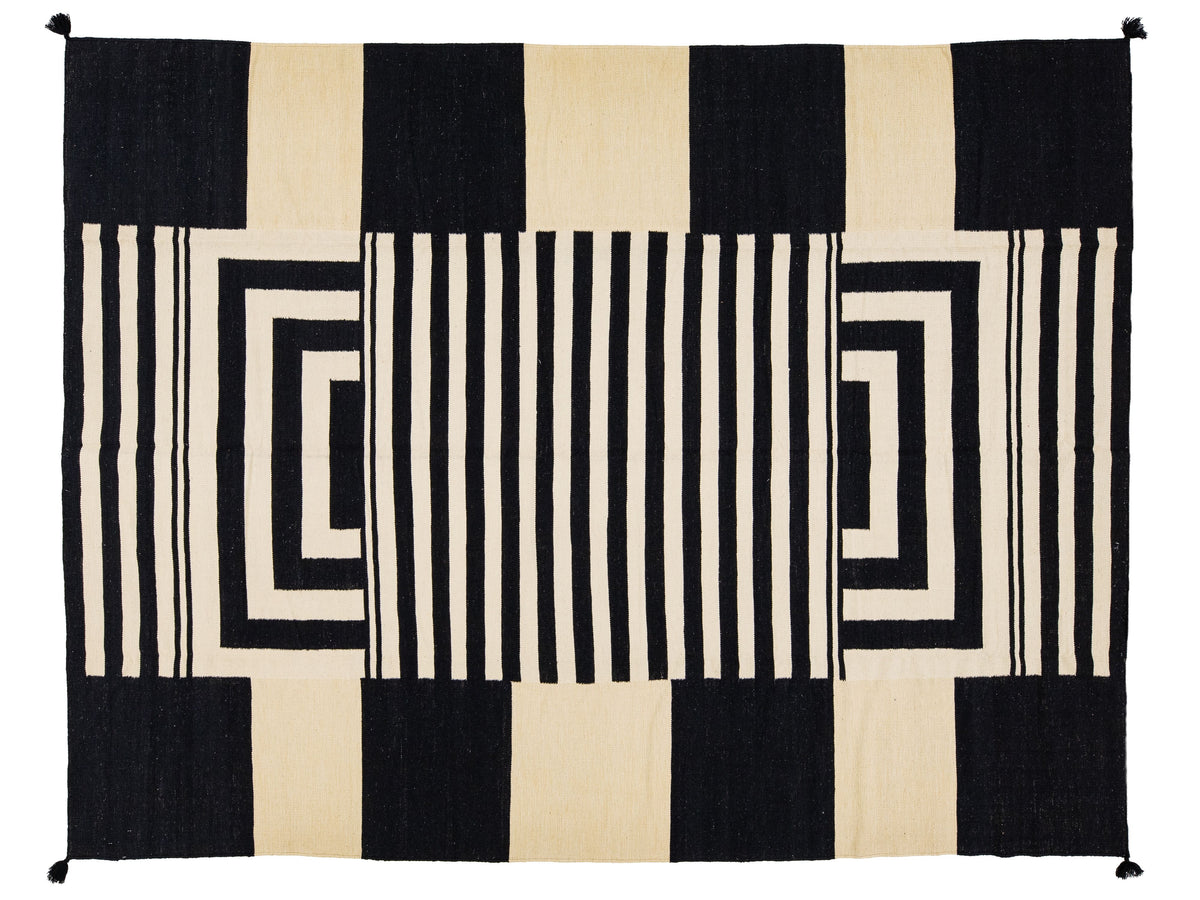 A rectangular woven rug with a bold geometric pattern in black and cream, featuring vertical stripes, concentric rectangular loops, and solid color blocks.