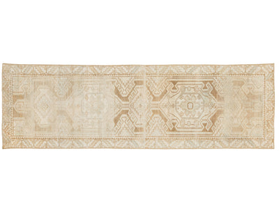 A runner rug with an intricate geometric and medallion pattern in beige, cream, and light brown tones, shown flat against a white background.
