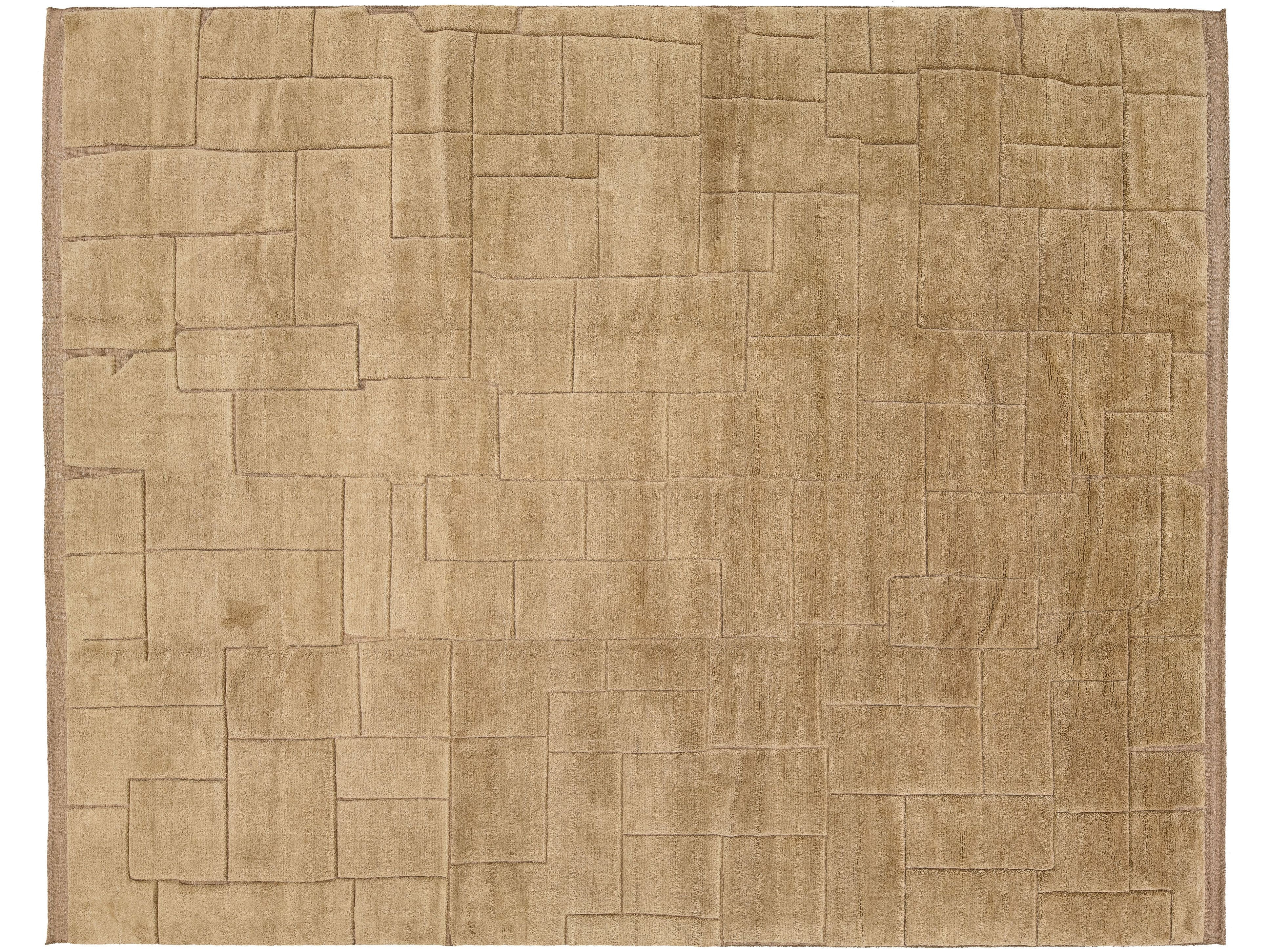A rectangular area rug with a textured, block-like geometric pattern in a warm tan or light brown color, shown flat against a white background.