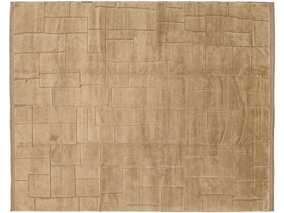 A rectangular area rug with a textured, block-like geometric pattern in a warm tan or light brown color, shown flat against a white background.