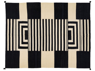 A rectangular rug with a bold geometric pattern of black and cream vertical stripes and nested rectangular blocks.