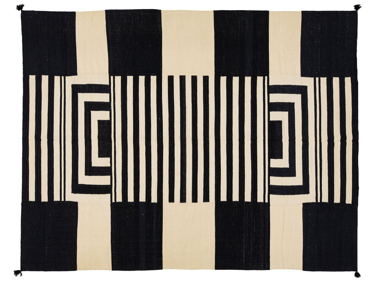 A rectangular rug with a bold geometric pattern of black and cream vertical stripes and nested rectangular blocks.