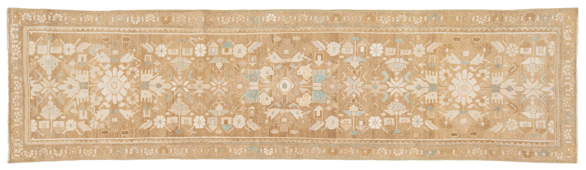 A runner rug with an intricate traditional pattern in beige, cream, and light blue, shown flat against a white background.