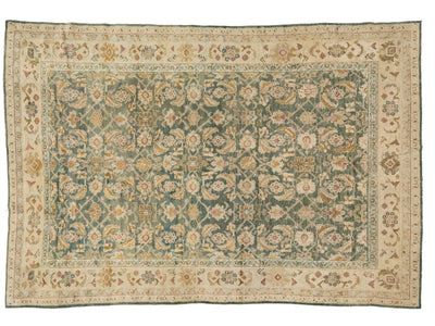 An antique oriental Agra rug with a teal-green center field, beige borders, and cream floral motifs.