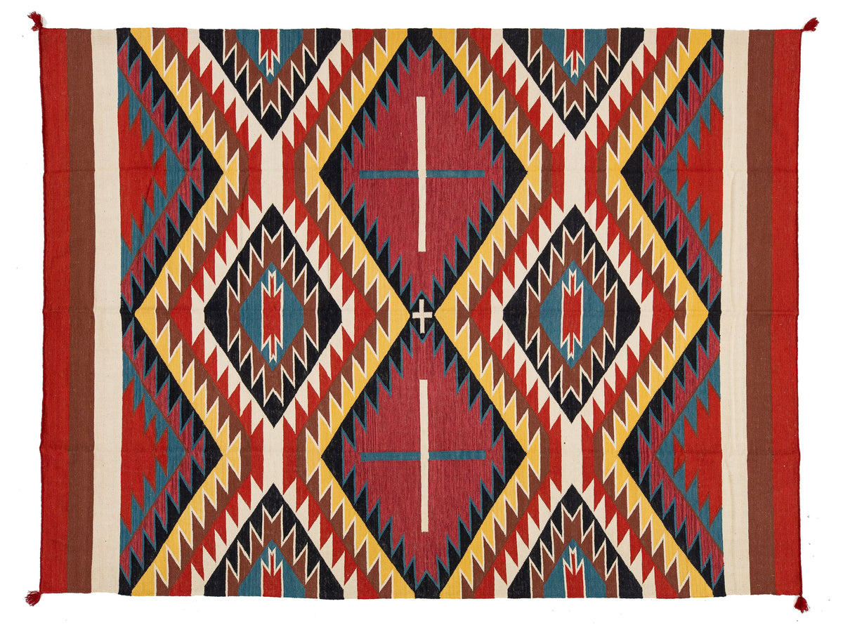 A Southwestern-style woven rug with a bold geometric pattern in red, yellow, black, blue, and beige, featuring diamond and zigzag motifs.