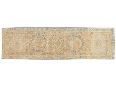 A runner rug with a distressed medallion pattern in beige, cream, and muted blue-gray tones, shown flat against a white background.