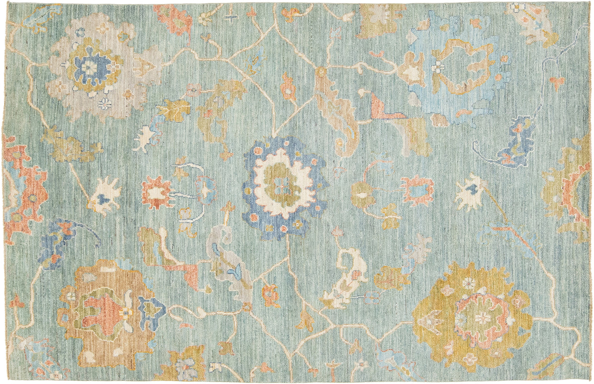 A rectangular area rug with a traditional floral pattern on a light blue-green background, featuring accents of yellow, coral pink, and soft blue.