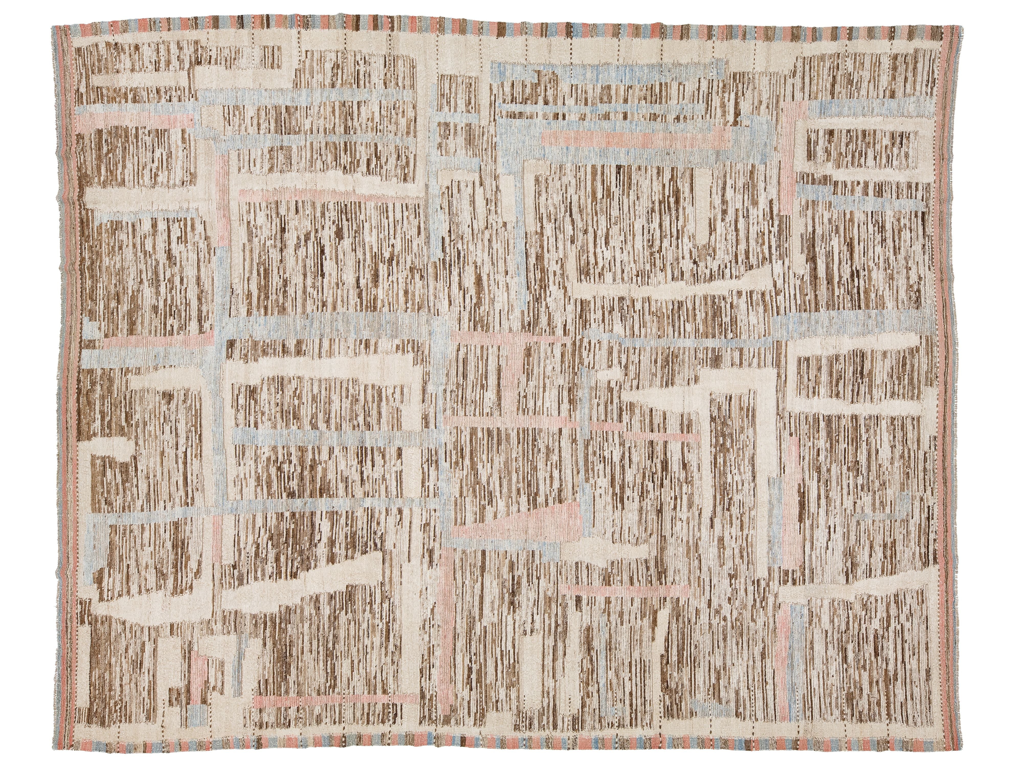 A square abstract patterned rug with a textured, woven appearance. The design features a grid-like layout with vertical brushstroke patterns in brown, beige, and cream, accented by light blue and pale pink lines.