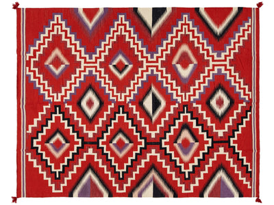 A rectangular woven rug with a bold geometric Southwestern-style pattern in red, cream, black, blue, and purple.