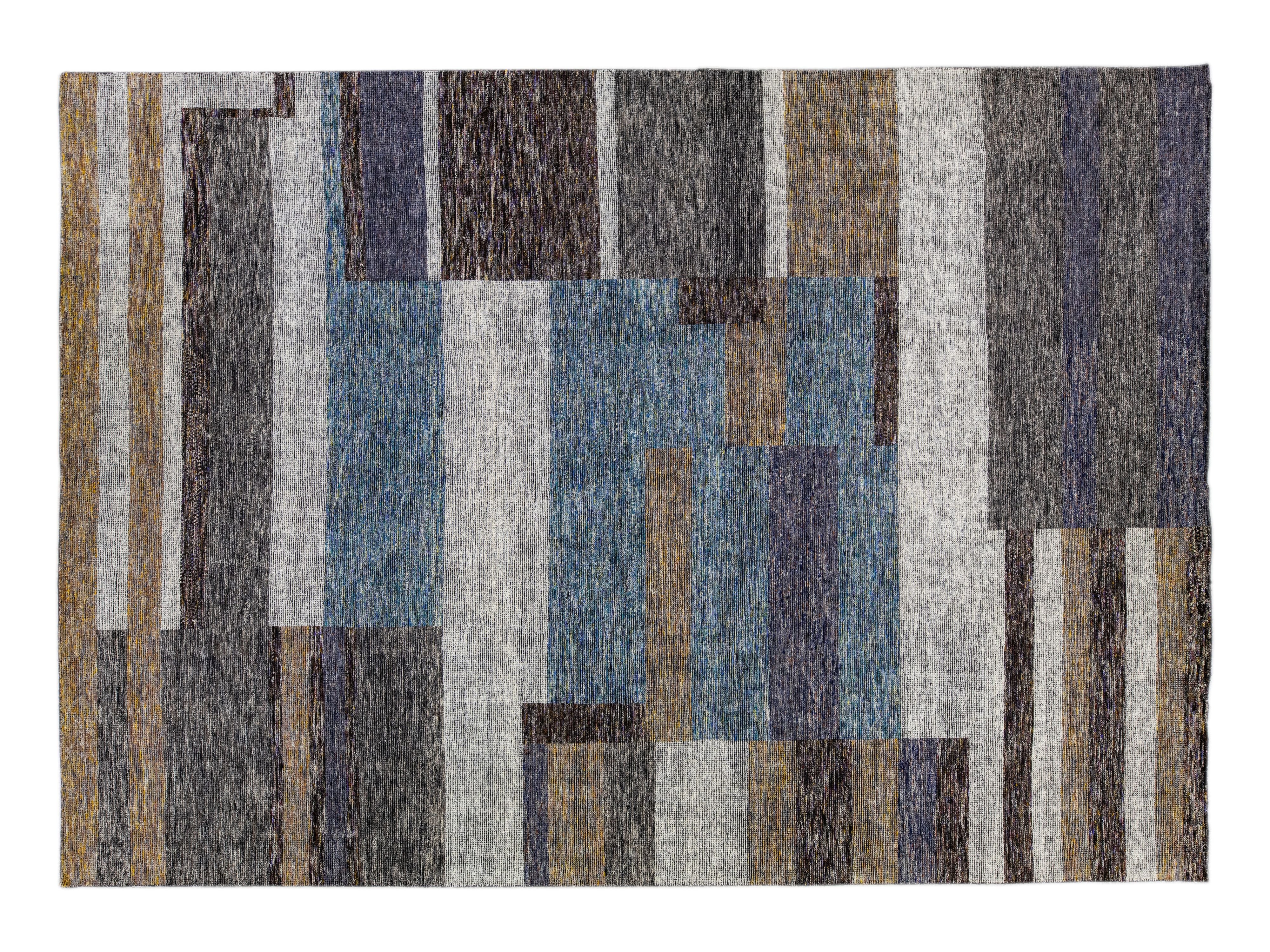 An abstract geometric area rug with a textured, heathered finish featuring blocks of blue, gray, brown, and navy.