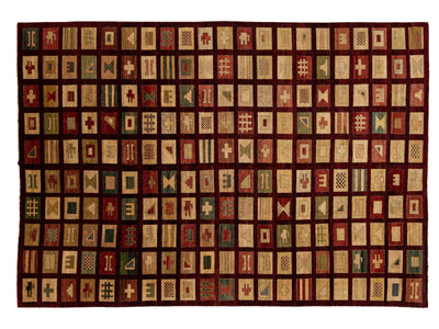 A rectangular modern quilt or rug featuring a grid of small geometric patch designs in cream, red, green, and brown on a dark red border.