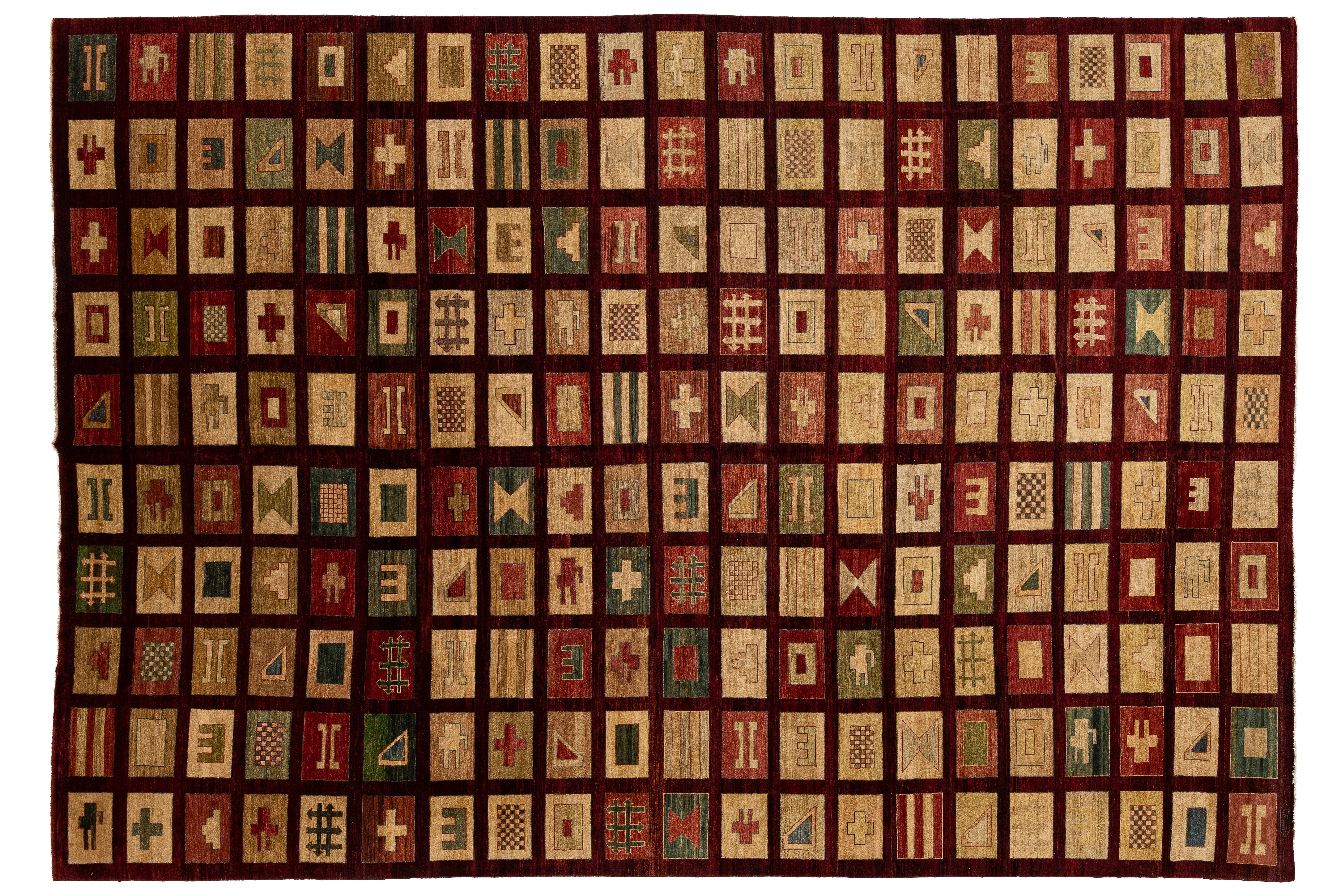 A rectangular modern quilt or rug featuring a grid of small geometric patch designs in cream, red, green, and brown on a dark red border.