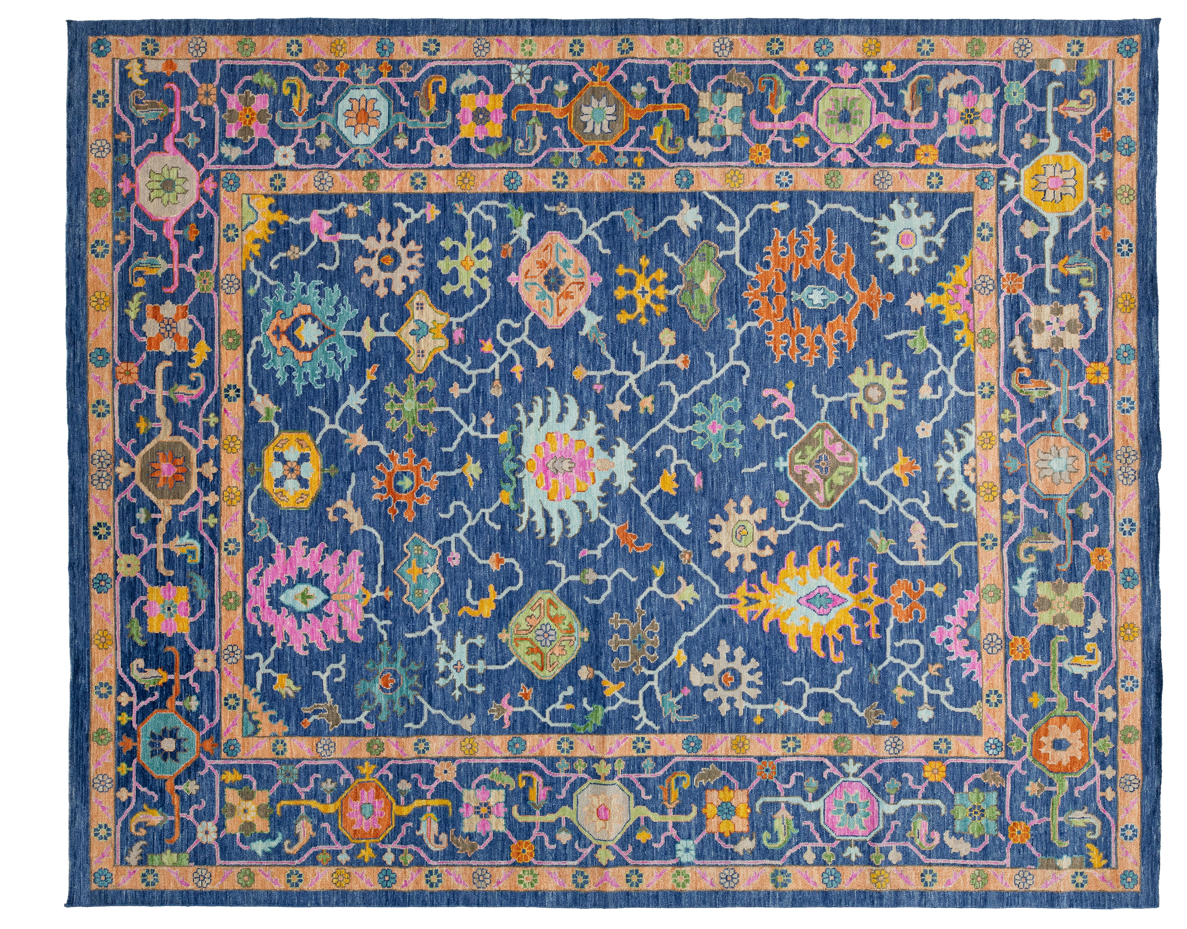 A rectangular traditional-style area rug with a navy blue field, pink border, and intricate multicolored floral and geometric motifs throughout.
