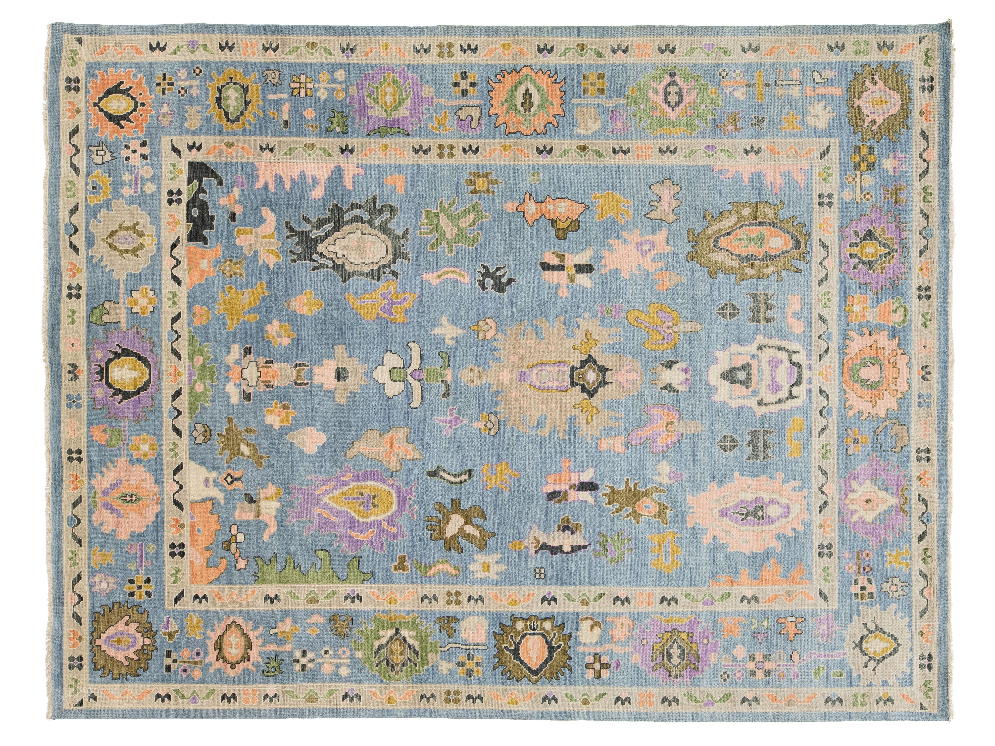 A rectangular area rug with a light blue central field and a detailed multicolor border and medallion pattern, shown flat against a white background.