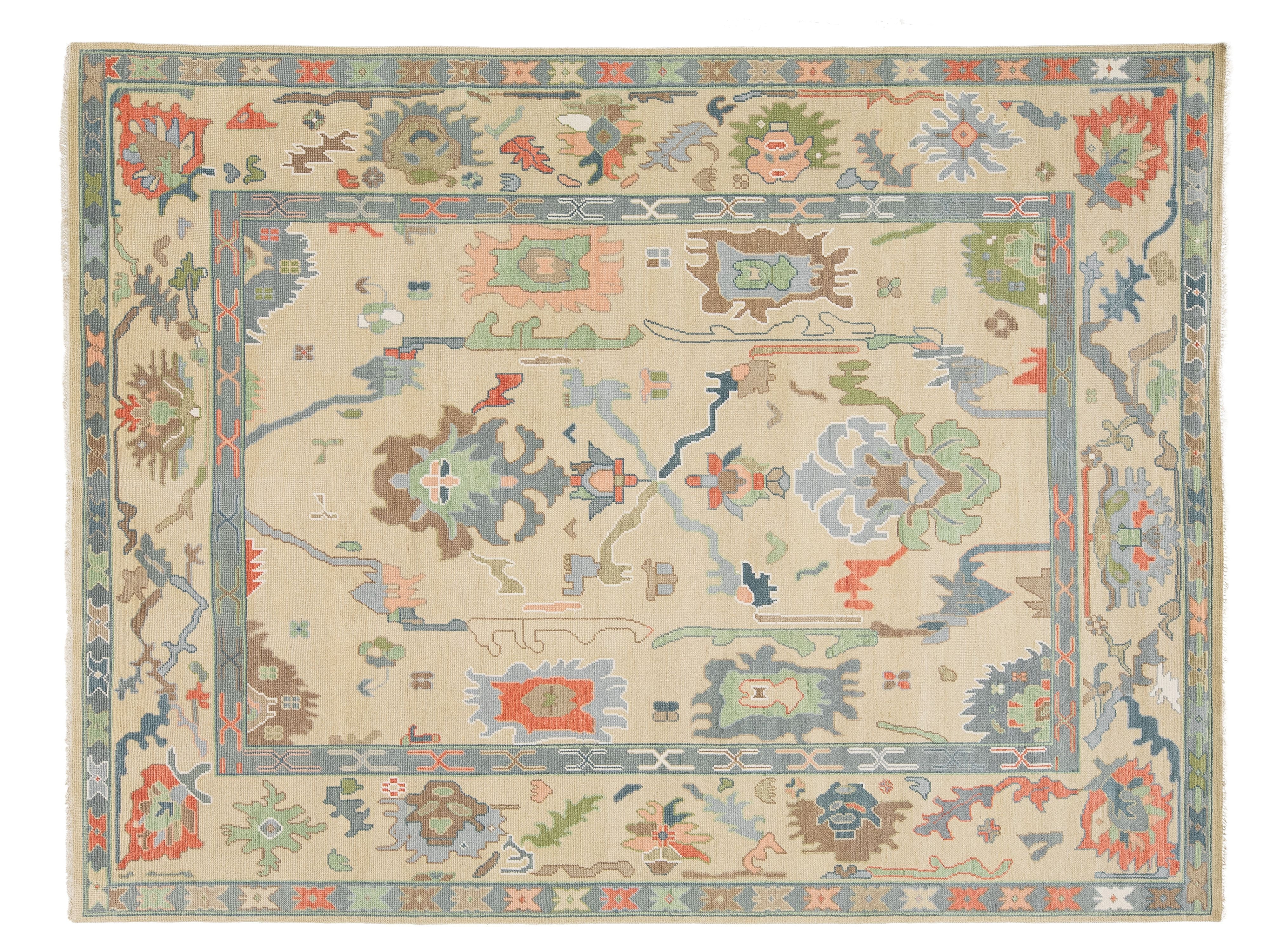 A rectangular oushak-style area rug with a cream-colored field and a detailed multicolor floral and geometric border pattern.