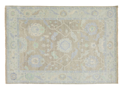 A rectangular area rug with a traditional floral and medallion pattern in muted beige, light blue, and pale green tones, shown flat against a white background.