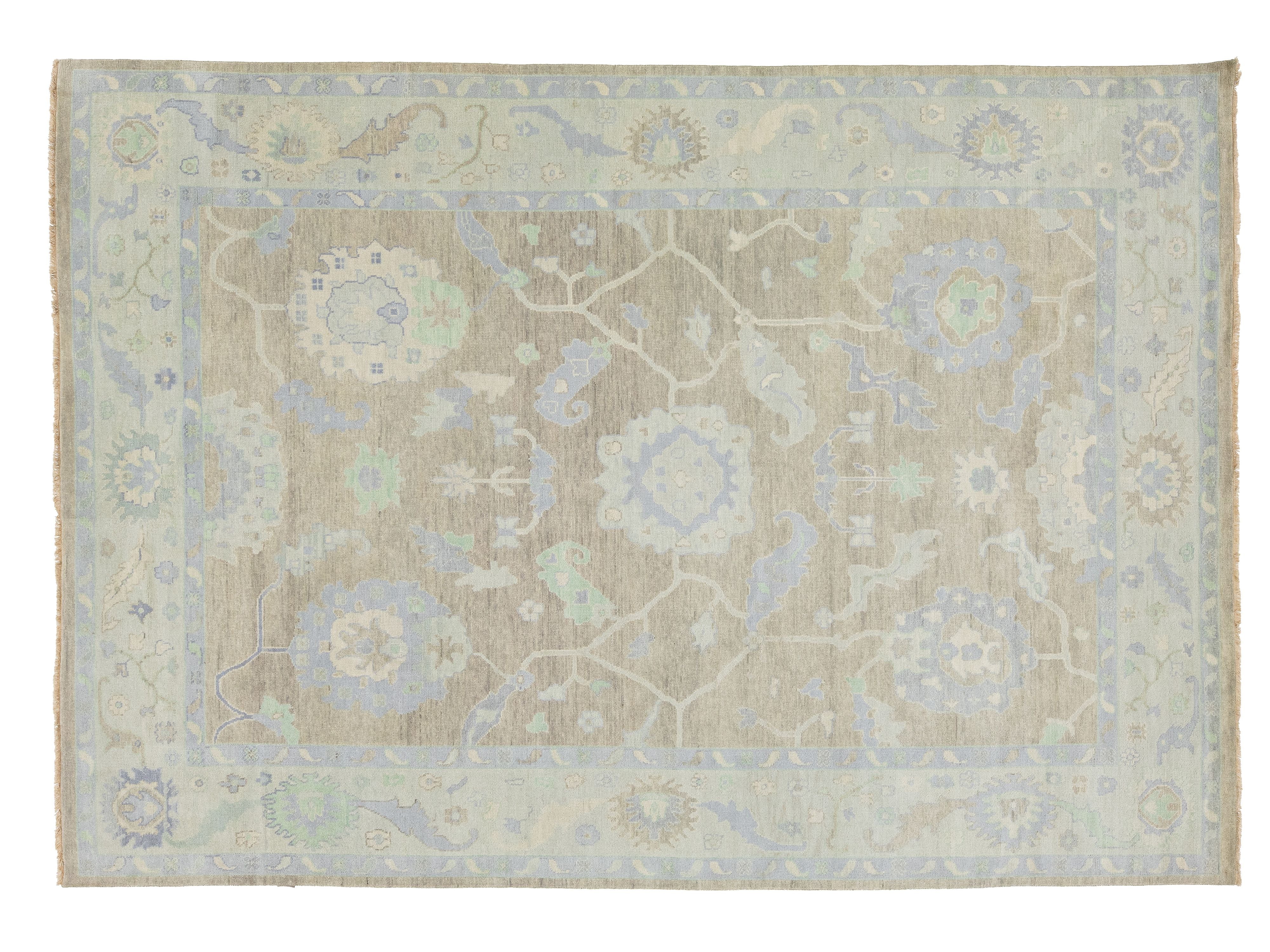 A rectangular area rug with a traditional floral and medallion pattern in muted beige, light blue, and pale green tones, shown flat against a white background.