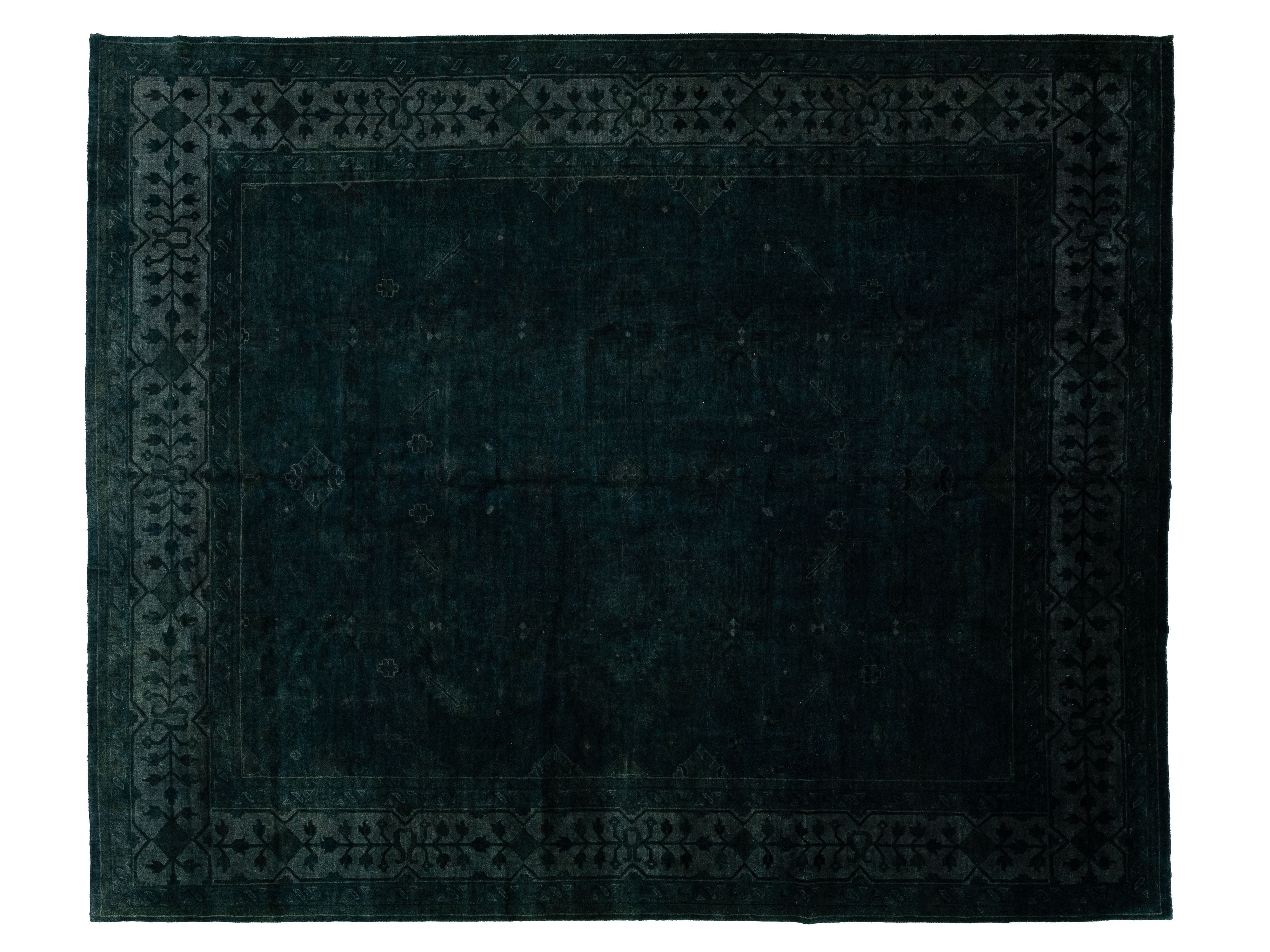 A dark green-navy blue rectangular area rug with a distressed, contemporary-style pattern and a decorative border, shown flat against a white background.