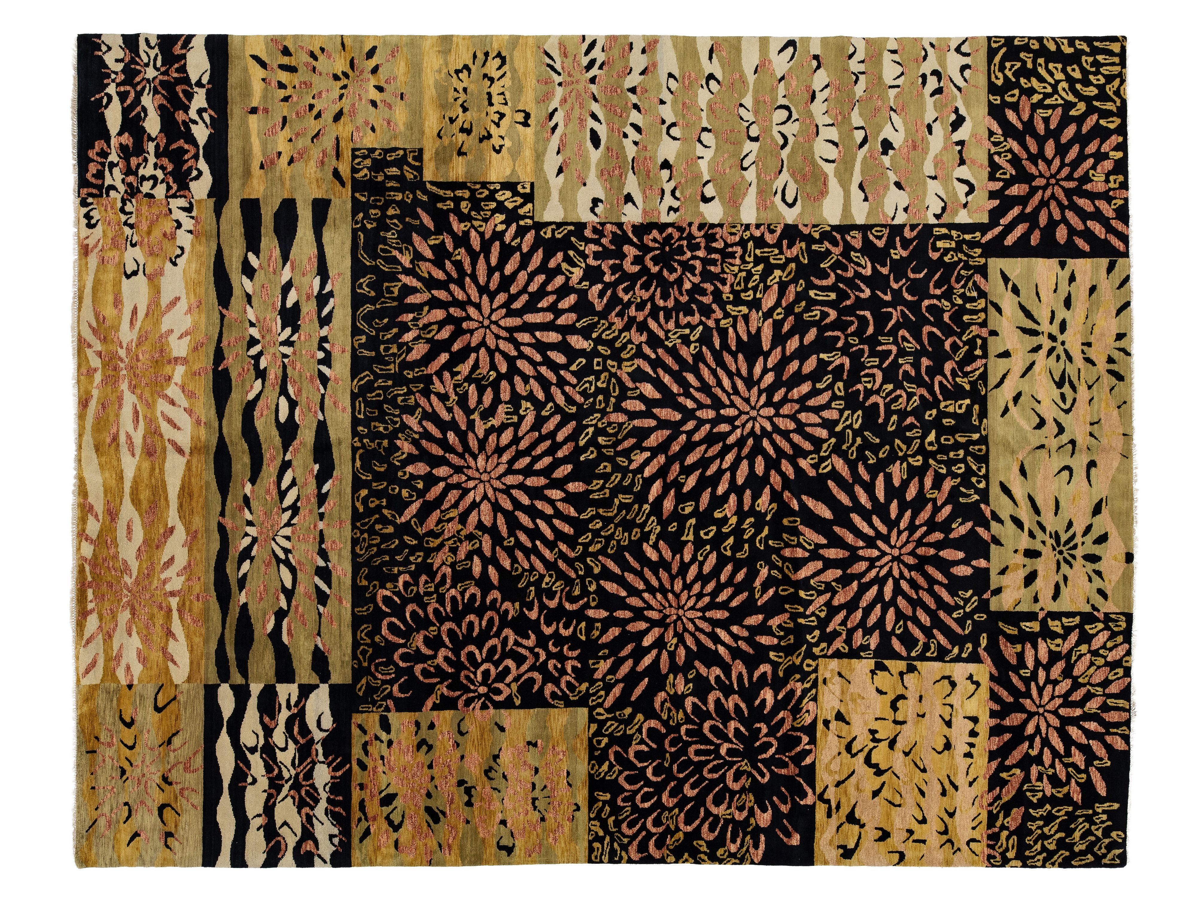 A rectangular rug featuring a patchwork design of rectangular panels with diverse batik-style floral, geometric, and wavy patterns in black, tan, beige, and muted pinkish-brown tones.