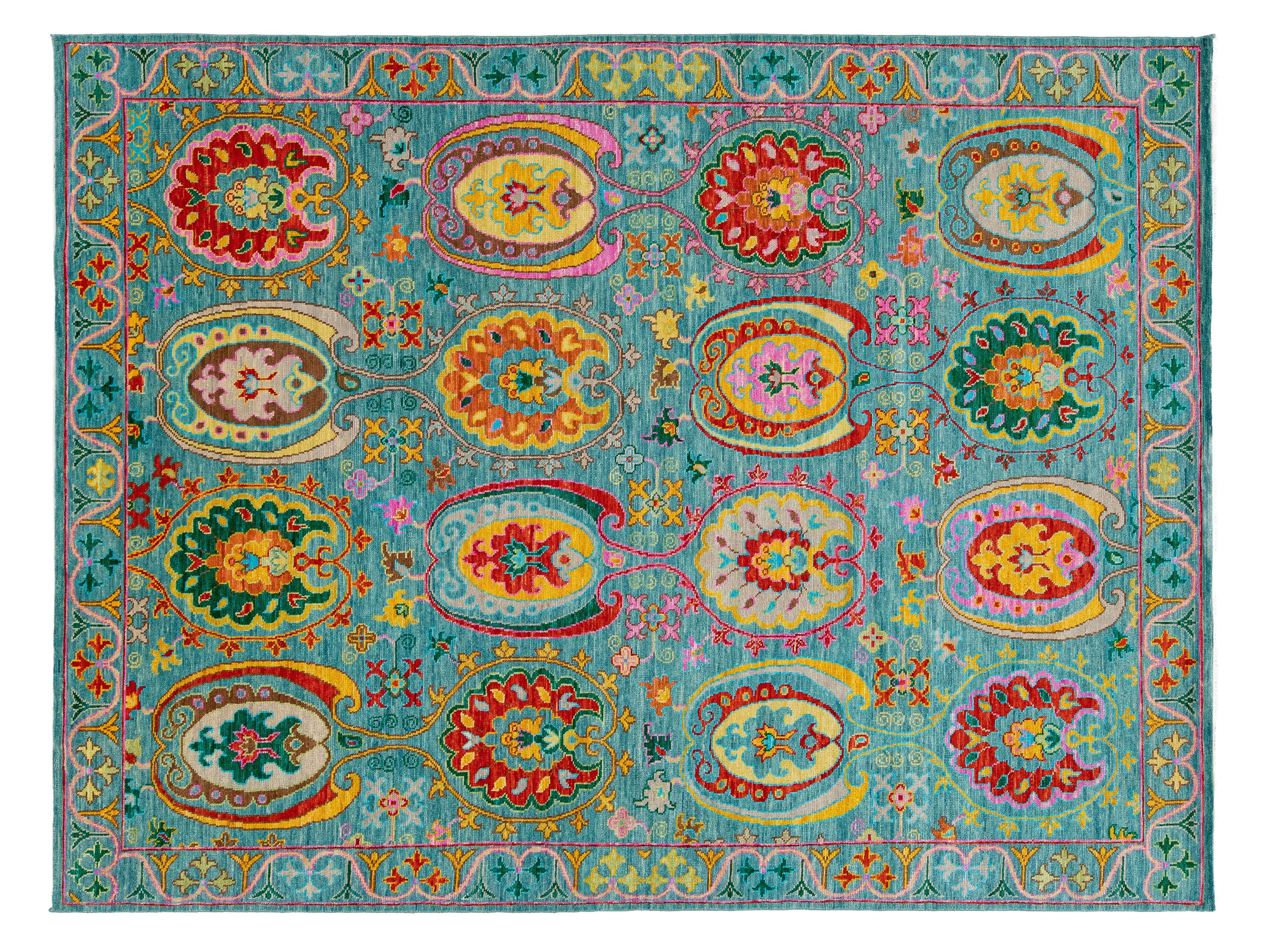 A rectangular turquoise blue area rug with a highly detailed, colorful traditional pattern featuring red, yellow, green, and pink floral and paisley motifs.