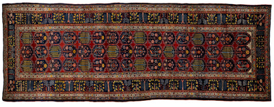 A traditional Persian-style runner rug with a deep red field, intricate blue, yellow, and black geometric and floral motifs, and a detailed border.
