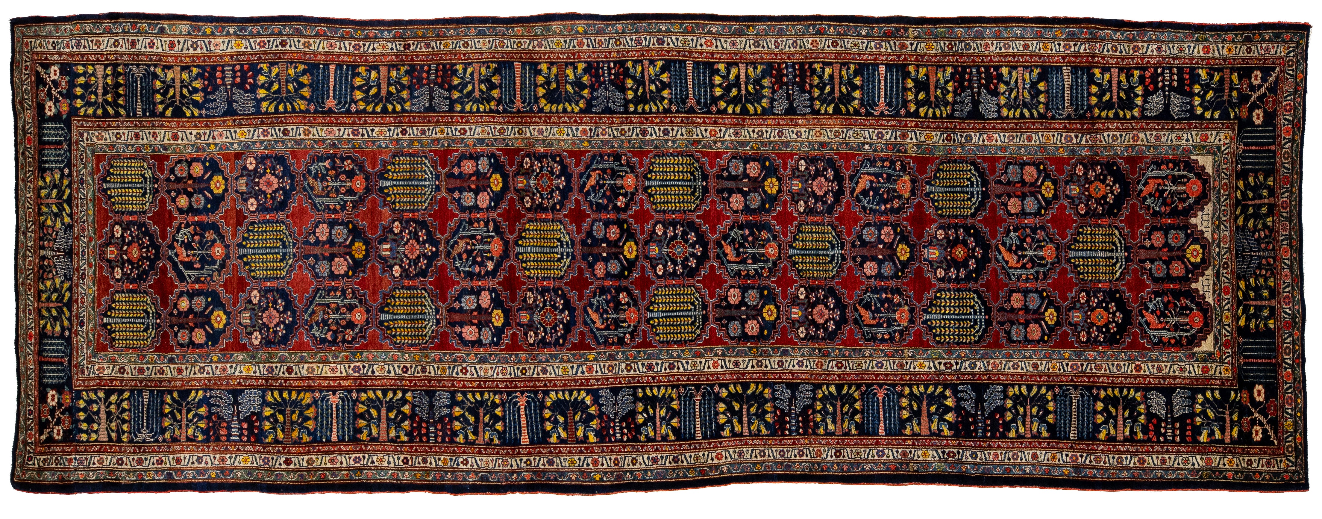 A traditional Persian-style runner rug with a deep red field, intricate blue, yellow, and black geometric and floral motifs, and a detailed border.