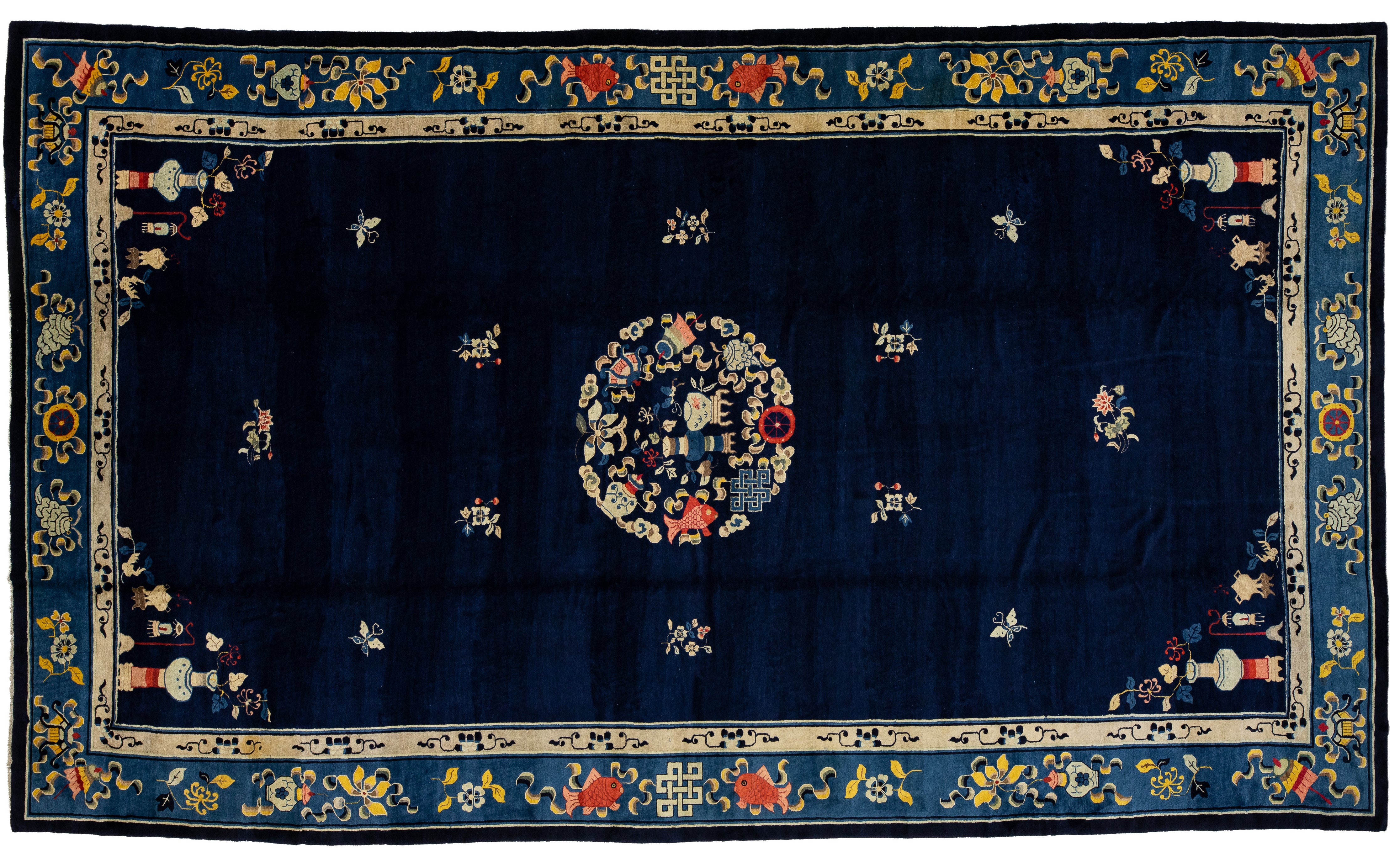 A rectangular navy blue rug with a central floral medallion, surrounded by small floral motifs and a decorative border in beige, blue, red, and yellow.