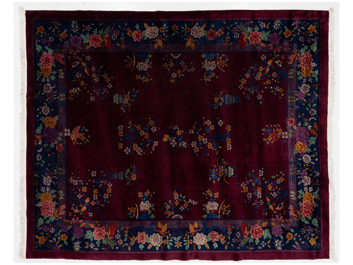 A traditional oriental Chinese rug with a deep burgundy center field, a dark navy floral border, and multicolored floral motifs throughout.