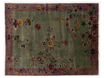 A rectangular Chinese floral rug with a muted olive green center field, a dusty mauve-purple border, and scattered embroidered or woven floral motifs in red, yellow, blue, and green.