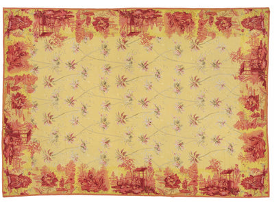 A rectangular textile or rug with a pale yellow base and a red toile-style border and scattered floral motifs, shown flat against a white background.