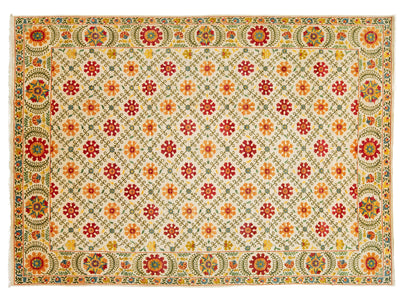 A rectangular area rug with a cream-colored field, featuring a repeating pattern of red and orange floral medallions, surrounded by a detailed multicolor border with green, yellow, and red motifs.
