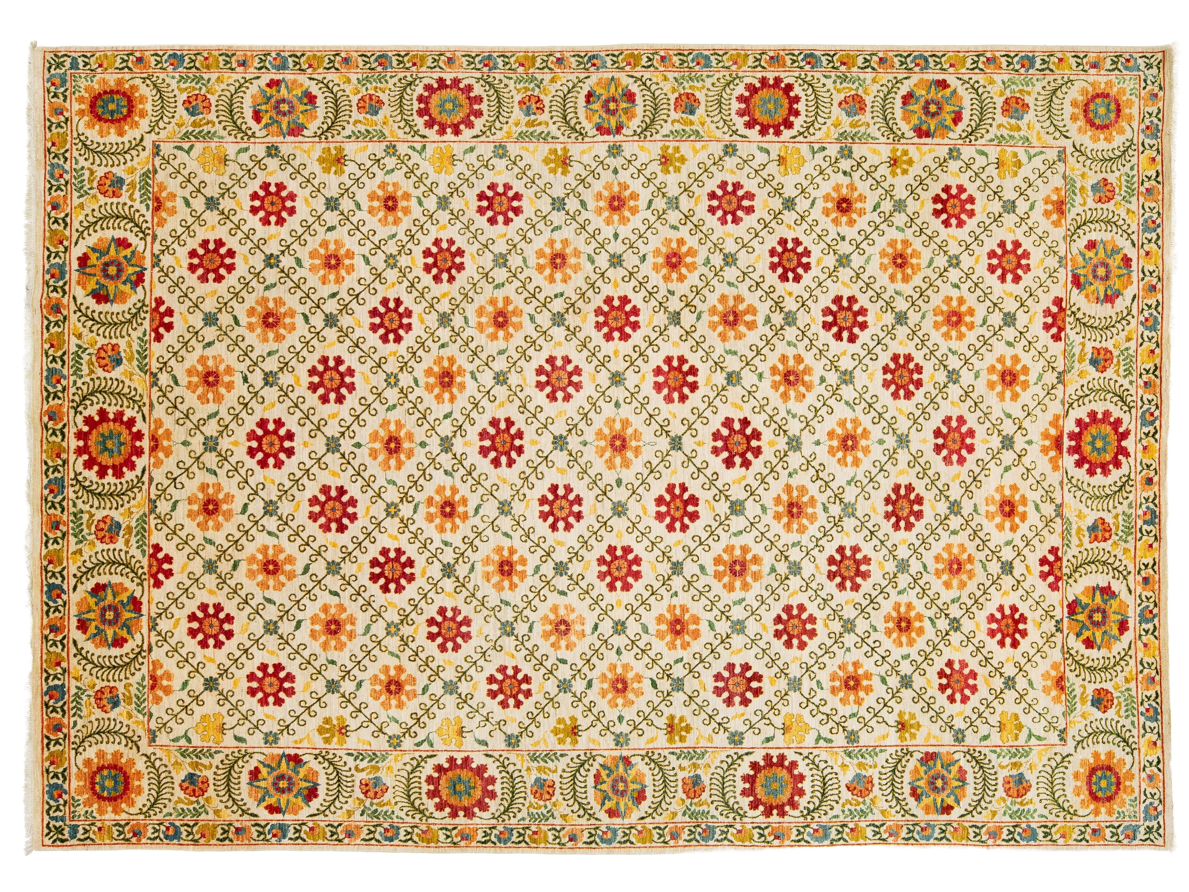 A rectangular area rug with a cream-colored field, featuring a repeating pattern of red and orange floral medallions, surrounded by a detailed multicolor border with green, yellow, and red motifs.