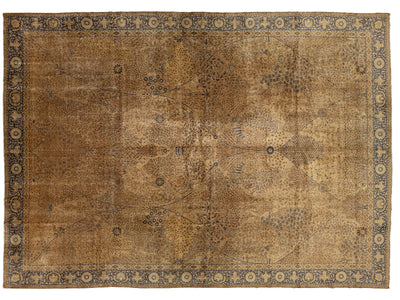 An antique oriental area rug with a faded design. The rug features a warm brown and beige center field with faded medallion motifs, surrounded by a dark navy blue border with circular floral patterns.