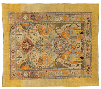 A square vintage Persian rug with a central medallion and ornate floral motifs, featuring a wide mustard yellow border and a multicolor pattern in orange, beige, blue, and brown.