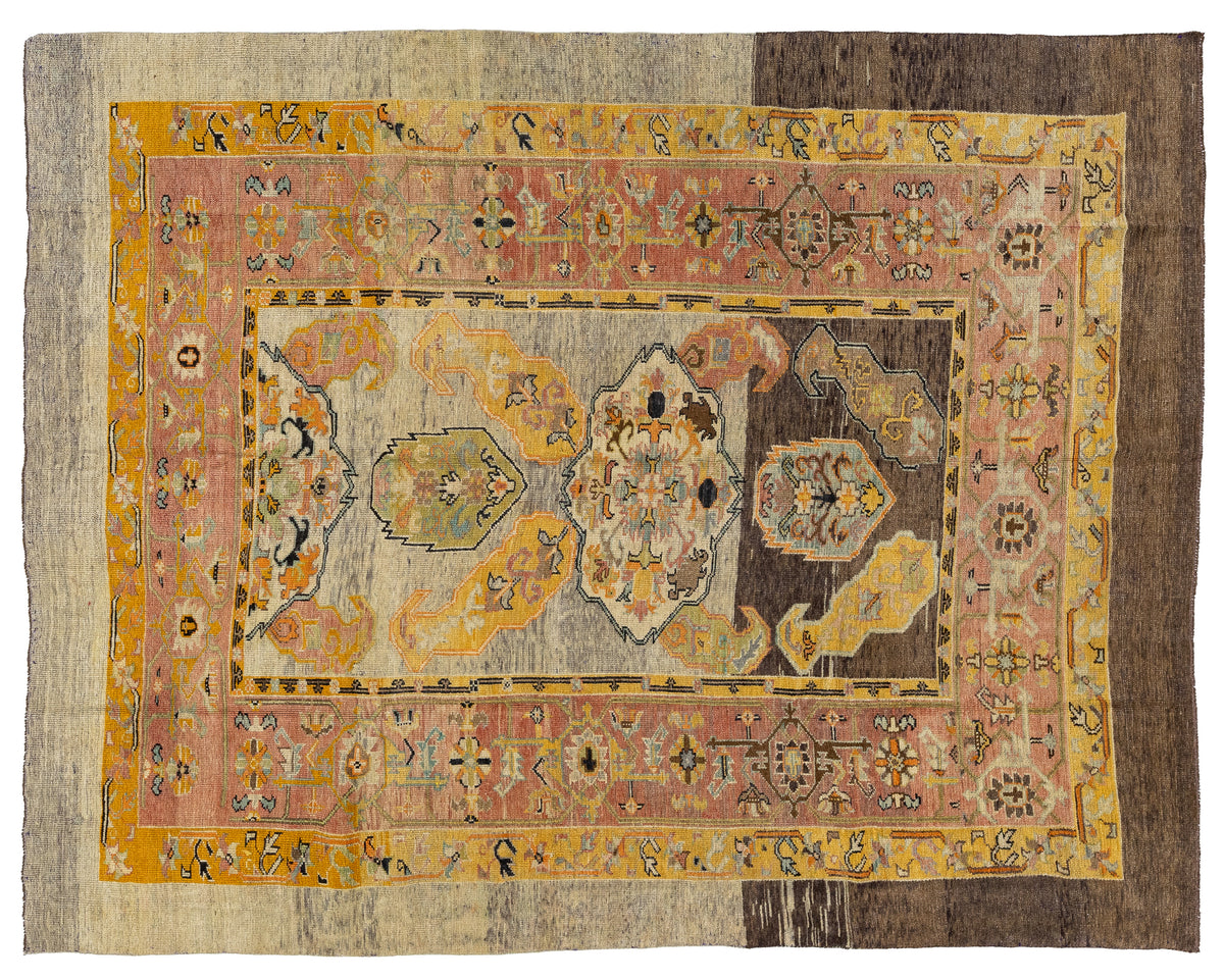 A vintage Persian wool rug with a distressed, vintage appearance, featuring a central floral medallion in muted tones of yellow, pink, gray, and brown, surrounded by ornate borders.