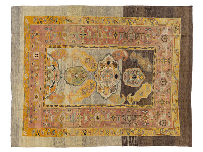 A vintage Persian wool rug with a distressed, vintage appearance, featuring a central floral medallion in muted tones of yellow, pink, gray, and brown, surrounded by ornate borders.