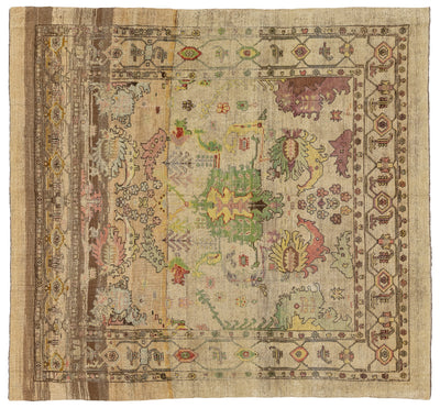 A square vintage area rug with a distressed, faded design. The rug features a beige and brown base with a central medallion and borders decorated with muted floral and geometric motifs in green, pink, yellow, and purple.