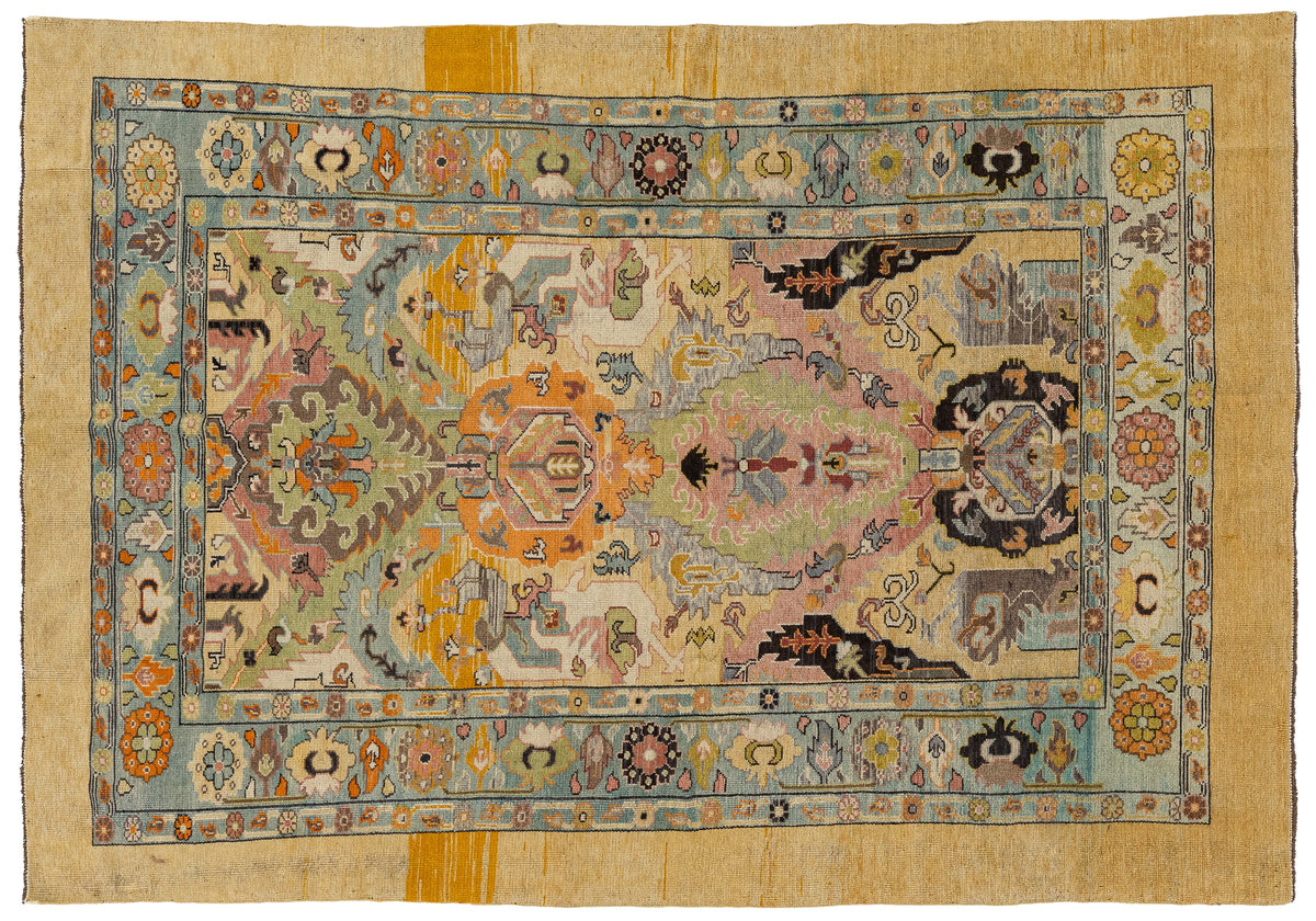An vintage Persian-style wool rug with a complex multicolor pattern, featuring a central medallion, floral borders, and a light beige/cream outer field.