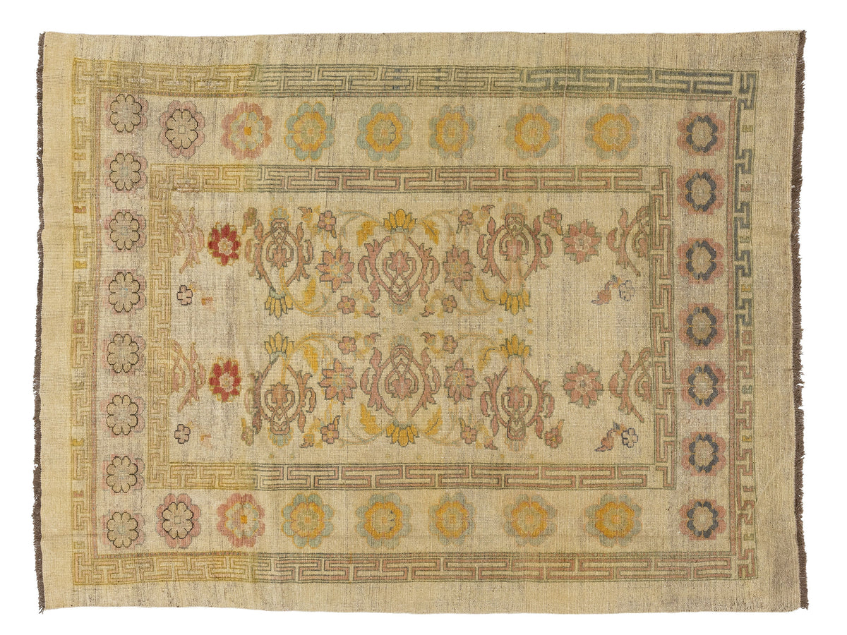 An vintage-style rectangular area rug with a distressed cream-beige field, featuring a central floral medallion motif and a decorative border with muted yellow, red, and blue accents.