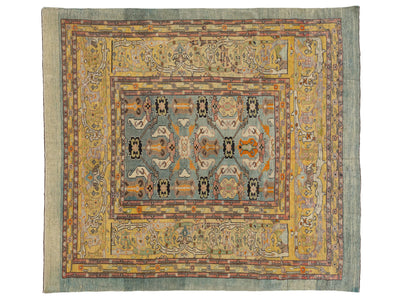 A vintage-style oriental rug with a complex geometric and floral pattern, featuring a central field of muted blue-gray, a wide golden-yellow inner border, and a dusty sage-green outer border.