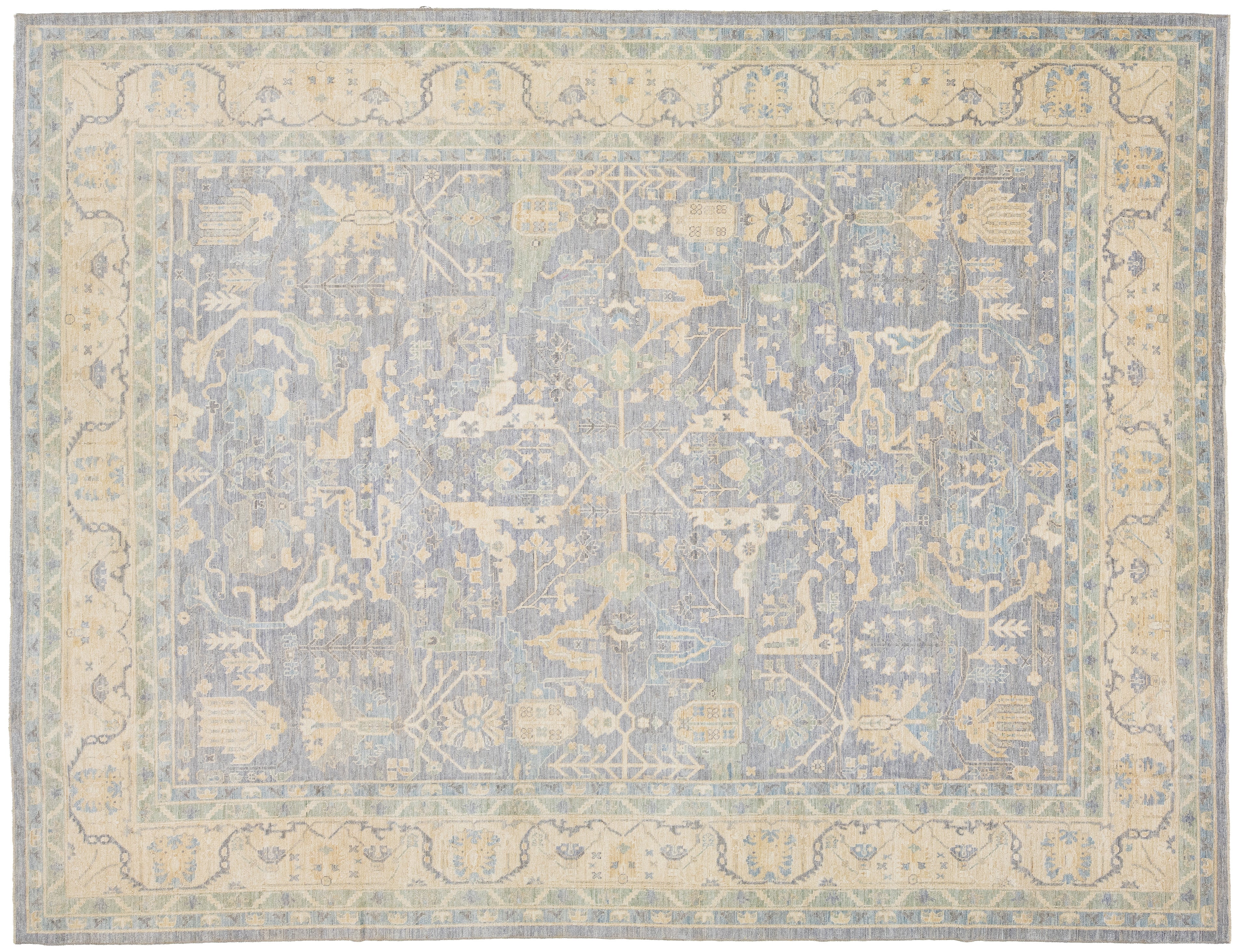 A rectangular oushak-style area rug with a faded traditional medallion pattern in muted blue-gray and warm beige tones.