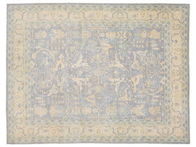 A rectangular oushak-style area rug with a faded traditional medallion pattern in muted blue-gray and warm beige tones.