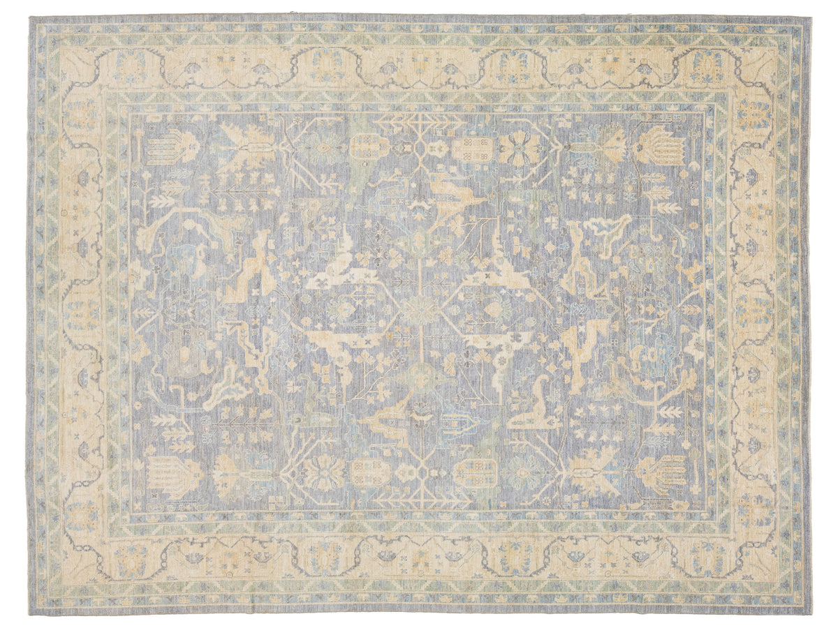 A rectangular oushak-style area rug with a faded traditional medallion pattern in muted blue-gray and warm beige tones.
