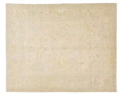 A rectangular area rug with a faded, traditional pattern in soft beige, cream, and muted sage green tones.