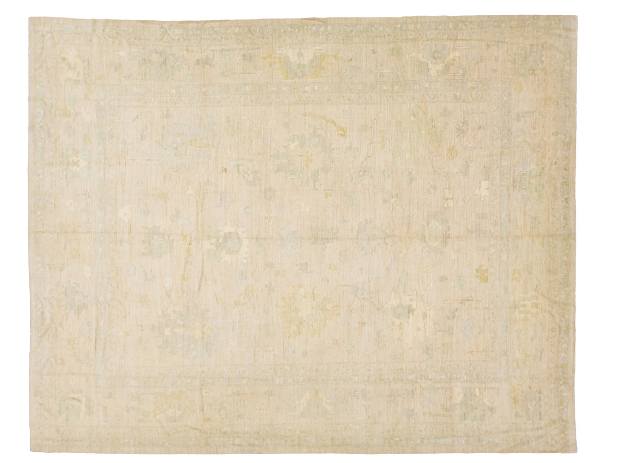 A rectangular area rug with a faded, traditional pattern in soft beige, cream, and muted sage green tones.