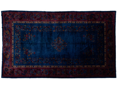 A rectangular traditional Chinese area rug with a deep blue central field, ornate floral motifs, and a dark red border with intricate detailing.