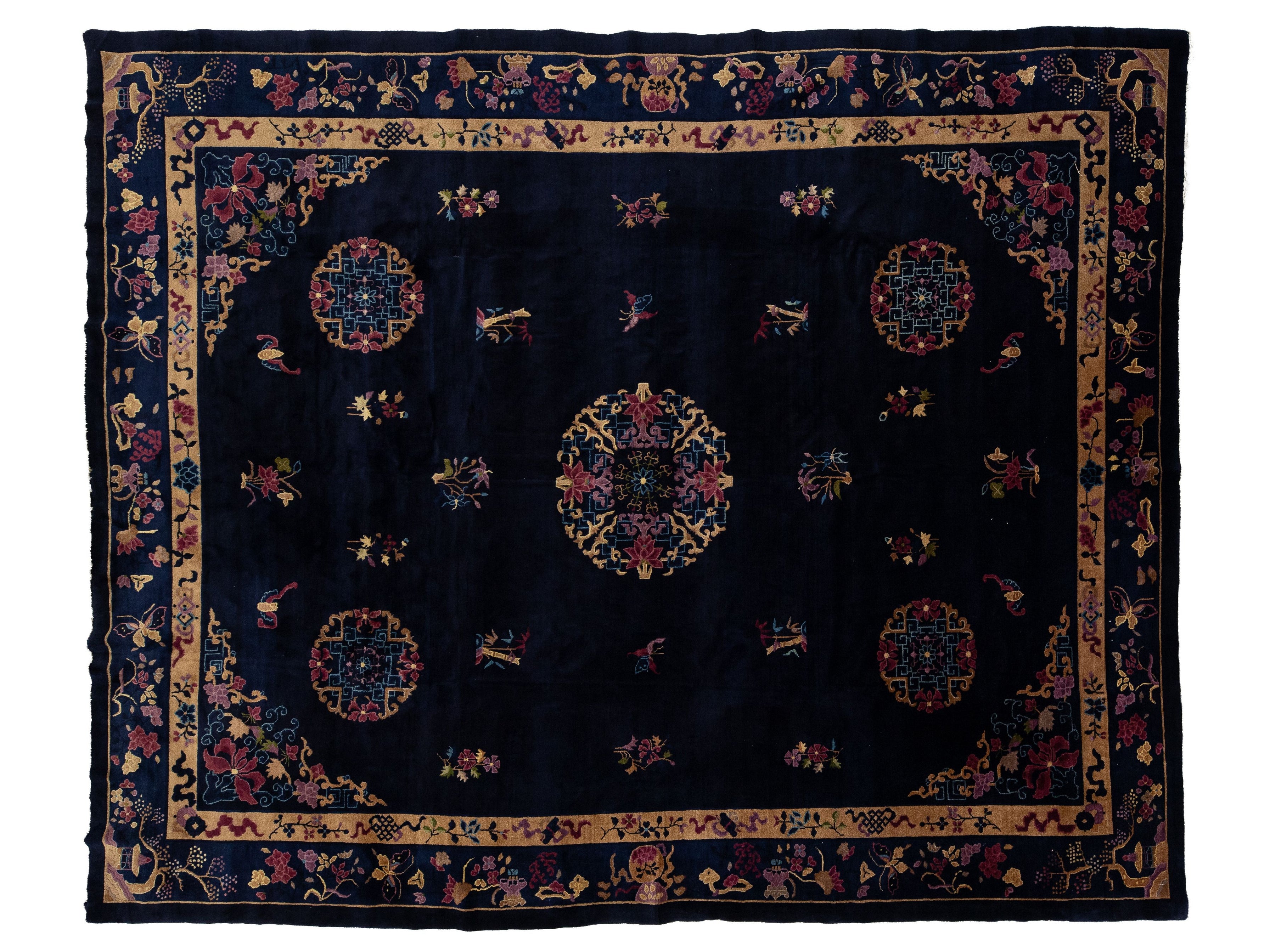 A dark navy blue oriental rug with intricate multicolor floral and geometric patterns, featuring a central medallion and a detailed border.