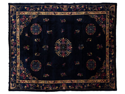 A dark navy blue oriental rug with intricate multicolor floral and geometric patterns, featuring a central medallion and a detailed border.