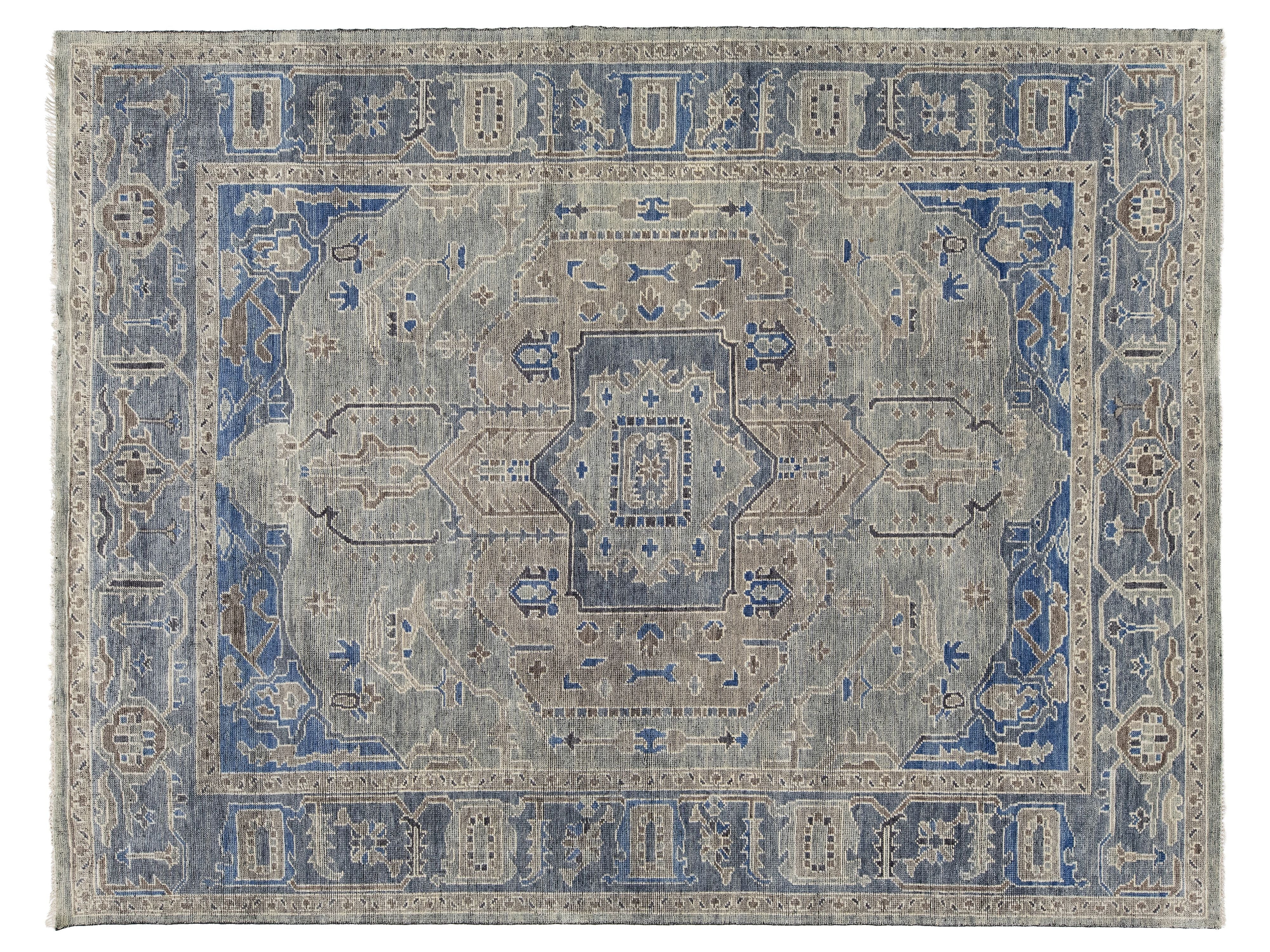 A rectangular oushak-style area rug with a distressed medallion pattern in muted blue, beige, and gray tones.