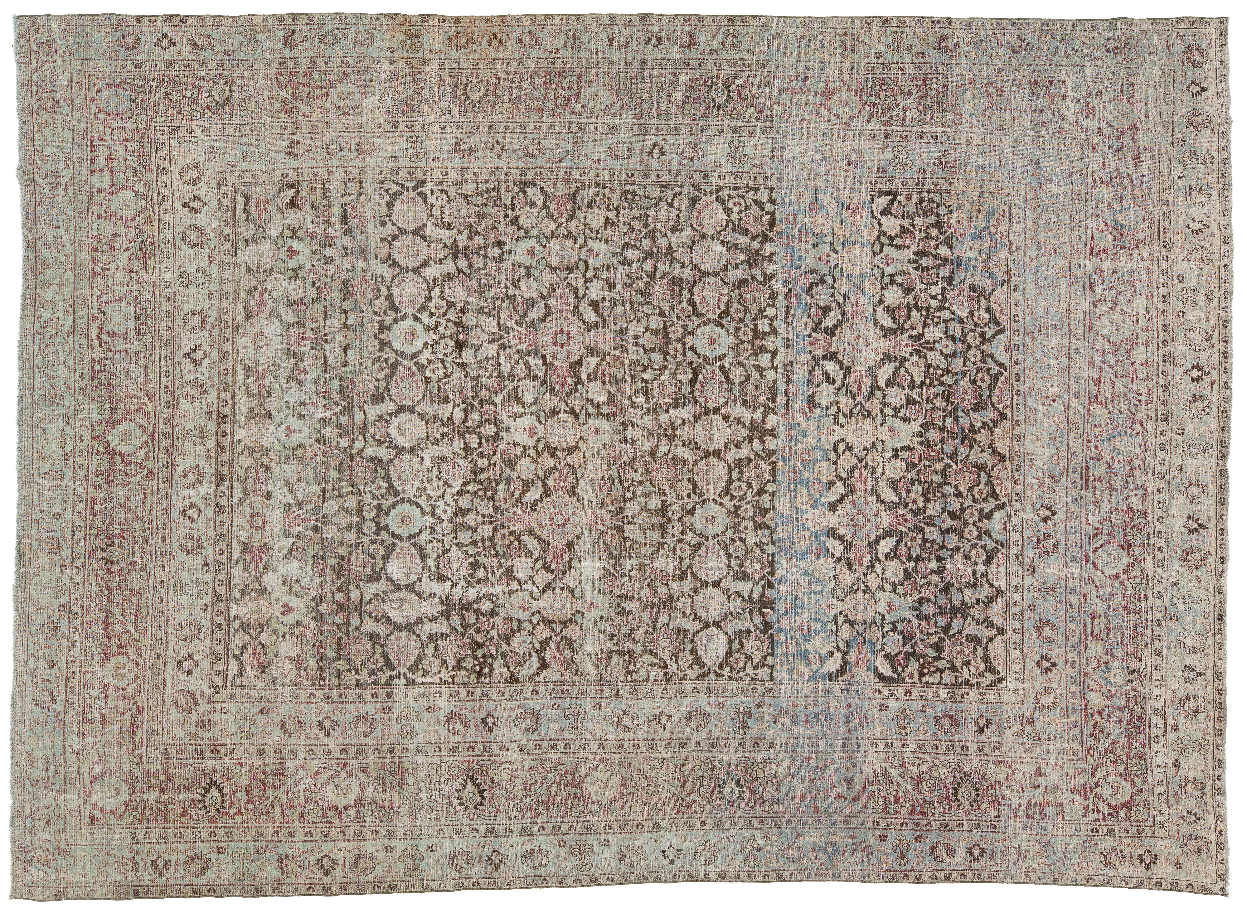 An antique-style oriental rug with a faded floral pattern, featuring a central field and multiple borders in muted tones of dusty pink, beige, gray, and light blue.